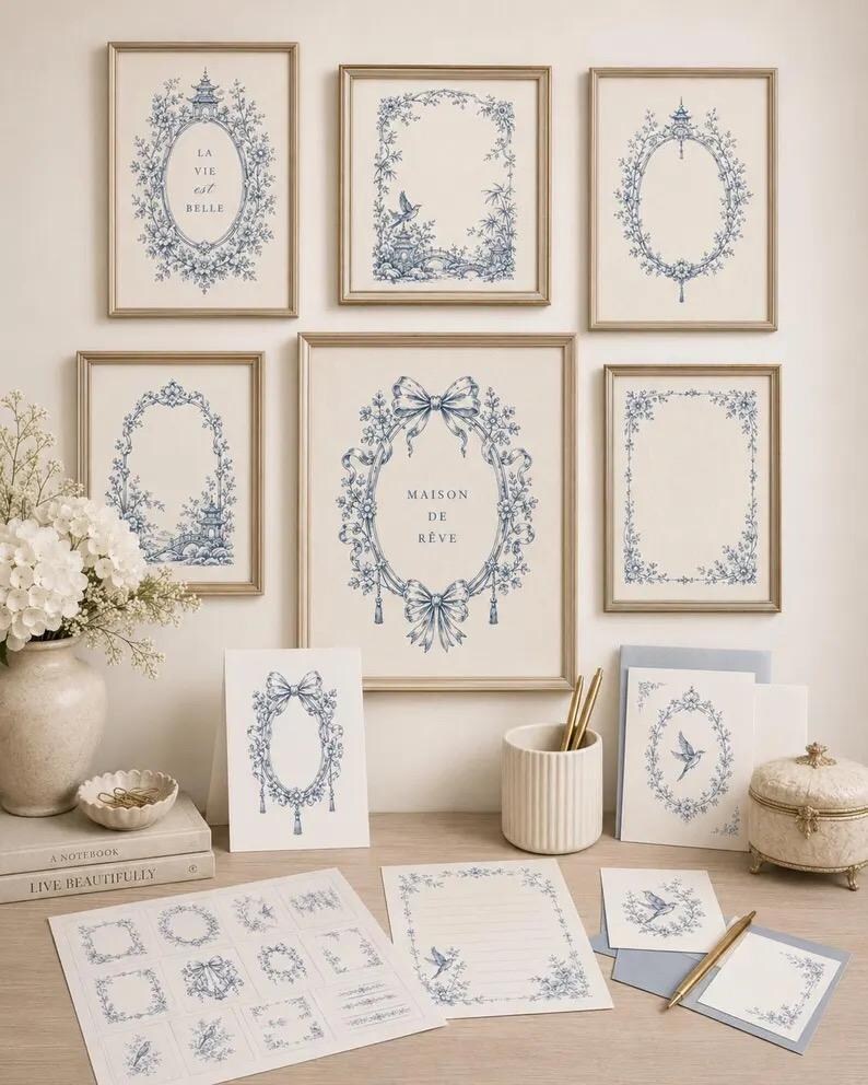 Pu&ograve; includere: Una collezione di stampe da parete e articoli di cancelleria con motivi floreali blu e bianchi in stile toile de Jouy. Le stampe includono il testo LA VIE est BELLE e MAISON DE R&Ecirc;VE, insieme a varie cornici ovali e rettangolari con motivi botanici.