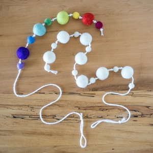 May include: A white string garland with white felt balls and a rainbow string of felt balls in various colors.