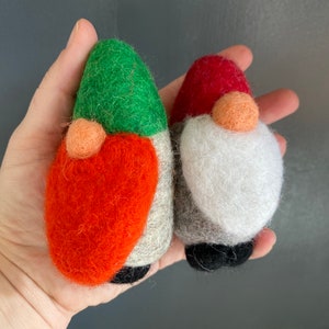 May include: Two felt gnome ornaments, one with a green hat and orange body, the other with a red hat and white beard.