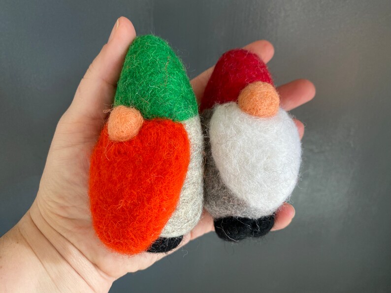 May include: Two felt gnome ornaments, one with a green hat and orange body, the other with a red hat and white beard.