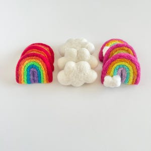 May include: Three felt rainbow arches and two felt clouds. The rainbows are layered with red, orange, yellow, green, blue, indigo, and violet. The clouds are white.