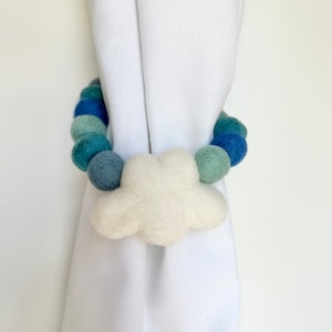 May include: A white felt cloud curtain tieback with a blue and green felt bead garland.