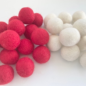 May include: A collection of red and white felt balls. The balls are soft and fluffy, and they would be perfect for a craft project or a decoration.