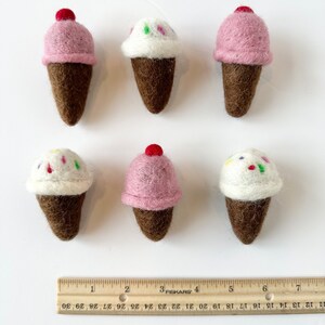 Pode incluir: Seis cones de gelado de feltro, tr&ecirc;s com gelado rosa e tr&ecirc;s com gelado branco. Os cones s&atilde;o castanhos e o gelado &eacute; decorado com granulado.