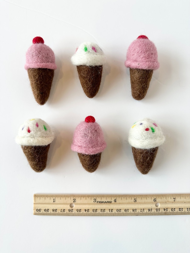 Pode incluir: Seis cones de gelado de feltro, tr&ecirc;s com gelado rosa e tr&ecirc;s com gelado branco. Os cones s&atilde;o castanhos e o gelado &eacute; decorado com granulado.