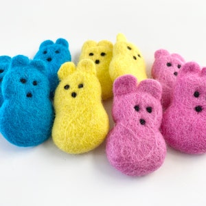May include: A set of nine felt Easter Peeps in blue, yellow, and pink. The Peeps are shaped like chicks and have black eyes.