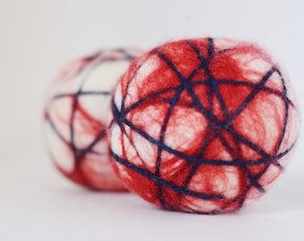 May include: Two felted wool balls, one red and white with blue yarn woven through it, and the other white with red yarn woven through it.