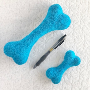 May include: Two blue felt dog bone toys. The larger bone is about 10 inches long. The smaller bone is about 5 inches long.