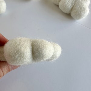 May include: A white felt cloud ornament with a rounded shape and a textured surface.
