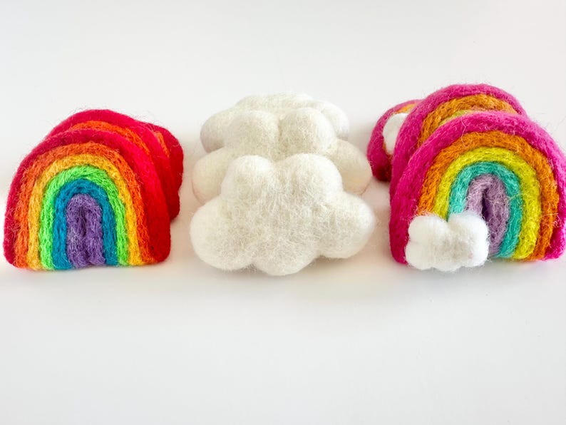 May include: Three felt rainbow arches and two felt clouds. The rainbows are layered with red, orange, yellow, green, blue, indigo, and violet. The clouds are white.