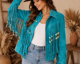 May include: A bright turquoise suede jacket featuring long fringe detailing along the sleeves and chest. The fringe is accented with small, cylindrical beads in shades of white and tan. The jacket has a classic collar, metal button closures, and long sleeves.