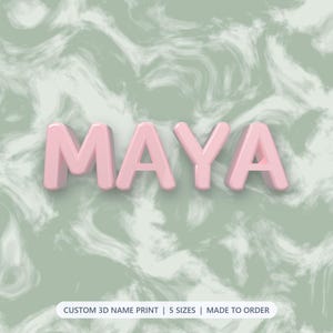 May include: The name MAYA in large, three-dimensional, light pink block letters centered against a sage green and white marbled background. Below the name, a white rectangular label contains the text: CUSTOM 3D NAME PRINT | 5 SIZES | MADE TO ORDER.