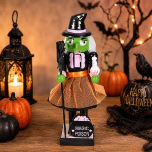 Peut inclure: Une figurine casse-noisette sorcière à la peau verte, portant un chapeau noir à étoiles jaunes et des cheveux blancs. Elle porte un haut noir à bordure rose et une jupe en tulle orange. Elle tient un balai noir et une fiole, sur un socle Magic Poison.