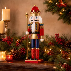 May include: A nutcracker figurine wearing a red and gold crown, a red jacket with gold trim, blue trousers, and red boots. The figure has a white beard, holds a tall gold staff, and stands on a rectangular red base with a black and gold finish.