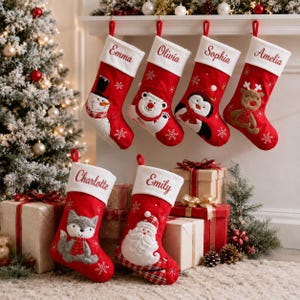 May include: Six red Christmas stockings with white cuffs, each personalised with embroidered names: Emma, Olivia, Sophia, Amelia, Charlotte, and Emily. The stockings feature appliqued characters including a snowman, polar bear, penguin, reindeer, fox, and Santa Claus, accented with white snowflake embroidery.