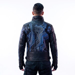 May include: A black leather jacket featuring a vibrant blue and white circuit board pattern printed across the back and sleeves. The jacket includes a high collar, ribbed shoulder and lower back panels, and black plastic buckle strap details.