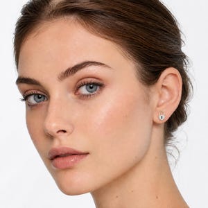 May include: A small silver-toned stud earring shaped like a heart-shaped padlock. The earring features a metallic finish with a central keyhole detail, designed to be worn on the earlobe as a singular piece of jewelry for everyday wear.