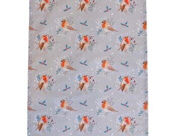 May include: A gray tea towel with a repeating pattern of robins, holly sprigs, and stars. The robins have red breasts and brown wings. A white loop is attached to the top corner for hanging.