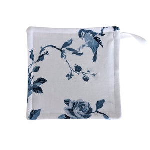 May include: A white cotton pot holder with a blue floral and bird design. The design features blue roses, leaves, and birds on a white background.