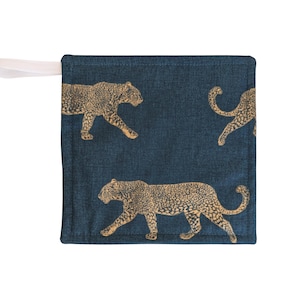 May include: A navy blue square pot holder with a cream loop. The pot holder has a repeating pattern of tan leopard illustrations. The leopard illustrations are walking across the surface of the pot holder.
