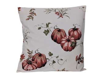 May include: A white throw pillow with a fall-themed design featuring red and green pumpkins with vines and leaves.