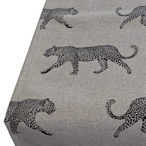 Könnte beinhalten: Eine grau-weiße Tischdecke mit einem sich wiederholenden Muster aus schwarzen Leoparden. Die Leoparden sind in einem realistischen Stil gedruckt.