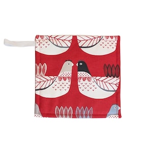 May include: A square, red potholder with a white loop for hanging. The potholder features a repeating pattern of stylized white and gray birds with black accents and leaf details. The birds are set against a red background.