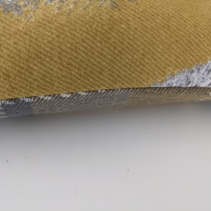 May include: A yellow and gray patterned throw pillow with a textured fabric.