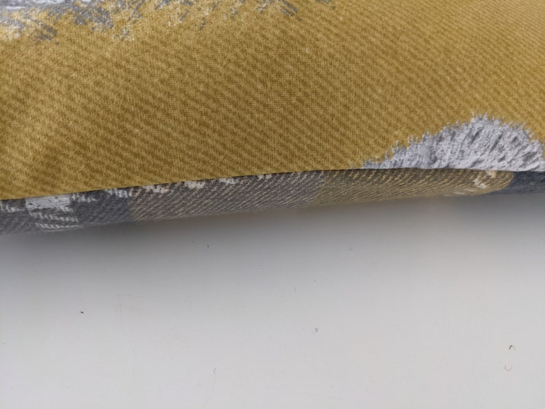 May include: A yellow and gray patterned throw pillow with a textured fabric.
