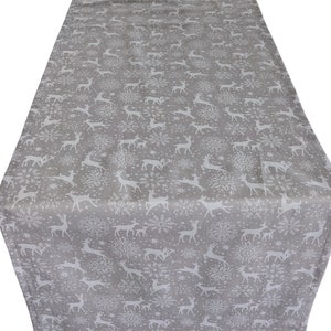 May include: A grey table runner featuring a repeating pattern of white reindeer and snowflakes. The runner is rectangular and made of fabric, suitable for festive or winter decor.