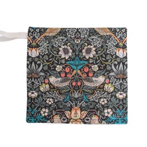 May include: Square fabric pouch with a detailed floral and bird pattern in shades of black, teal, orange, and white. The design features symmetrical arrangements of flowers, birds, and berries. A white ribbon is attached to the side.