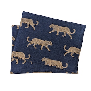 May include: Two blue fabric placemats with a repeating pattern of gold leopard silhouettes.