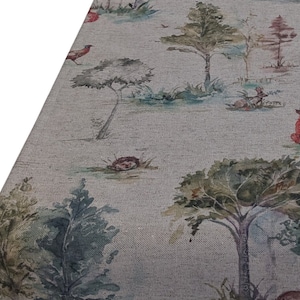 May include: A linen table runner with a watercolour forest design. The scene depicts trees, a fox, deer, and a pheasant. The colour scheme is soft, with greens, browns, and blues, creating a natural, rustic aesthetic.