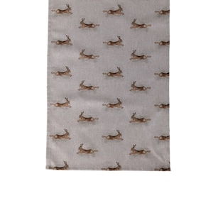 Può includere: Un runner da tavolo in lino grigio con un motivo ripetitivo di lepri marroni che corrono.