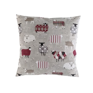 May include: A grey throw pillow with a red, white and black plaid pattern featuring a repeating design of sheep wearing different coloured sweaters.
