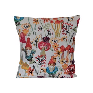 May include: A white cushion featuring a colourful pattern of mushrooms, gnomes and flowers. The design is in a watercolour style with a whimsical feel.