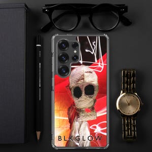 May include: A clear phone case with a red, white, and black design. The design features a figure with a white mask and black eyes. The text "BLK GLOW" is printed on the bottom of the case.