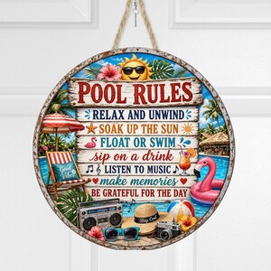May include: A round hanging sign with a weathered metal border featuring the text POOL RULES and a list of activities. The design includes a sun with sunglasses, a beach chair, a pink flamingo float, a boombox, a straw hat, and sunglasses.