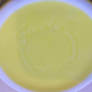 May include: The underside of a bright yellow ceramic mug featuring the embossed script text Fiesta and the letters HLC USA. The circular base has a smooth, glossy finish with a slightly raised rim around the perimeter of the bottom surface.