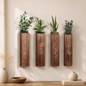 May include: Four rectangular dark brown wooden wall planters arranged vertically. Each planter features a unique, light-colored etched botanical line drawing on the front surface. Green plants are placed inside each of the four wooden containers.