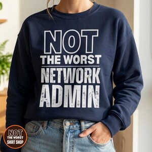 May include: A navy blue crewneck sweatshirt featuring the white text NOT THE WORST NETWORK ADMIN printed on the front. The word NOT is in a clean font, while the words THE WORST NETWORK ADMIN have a distressed, weathered texture.