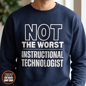 May include: A navy blue crewneck sweatshirt featuring white text that reads NOT THE WORST INSTRUCTIONAL TECHNOLOGIST. The design is centred on the chest with a clean, bold font style. A small circular logo in the bottom left corner repeats the text.