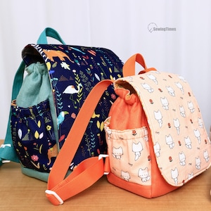 May include: Two fabric backpacks with drawstring closures and top flaps. The larger backpack is dark blue with a colorful nature print, while the smaller one is light orange with a white cat pattern. Both feature side pockets and adjustable straps.