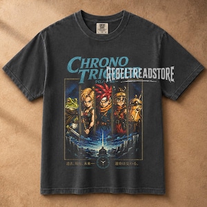 Può includere: Una t-shirt grigio antracite a maniche corte con una stampa grafica dei personaggi del videogioco Chrono Trigger. Il design include il testo Chrono Trigger, RebelTreadStore e caratteri giapponesi, con un'icona a forma di orologio in basso.