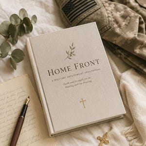 May include: A beige hardback book titled HOME FRONT A MILITARY DEPLOYMENT DEVOTIONAL Faith and Strength for the Waiting and the Praying with a small cross icon, accompanied by a fountain pen, a gold cross pendant, and a camouflage uniform.
