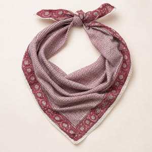 May include: A square bandana tied in a knot at the top, featuring a deep maroon and white colour palette. The centre displays a dense, repeating geometric pattern, while the border is decorated with a series of circular floral motifs.