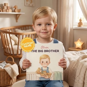 Puede incluir: Un libro infantil de tapa dura titulado Oliver, THE BIG BROTHER, con una ilustración de un niño pequeño sosteniendo un oso de peluche. La portada tiene una insignia circular amarilla que dice CUSTOM NAME y es sostenido por un niño.