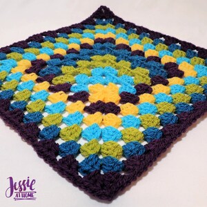 May include: A square crochet blanket with a geometric pattern in shades of purple, teal, green, and yellow. The blanket is made with a granny square stitch.