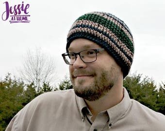 May include: A man wearing a striped crocheted beanie hat in shades of green, blue, and pink. He is wearing a light brown button-down shirt and glasses.