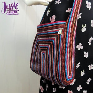 May include: A colorful crocheted bag with a striped pattern in shades of brown, red, blue, and gray. The bag has a long strap and is worn over the shoulder.